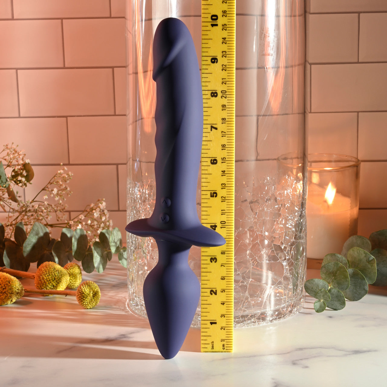 A purple dual-ended silicone vibrator with a ruler for scale.