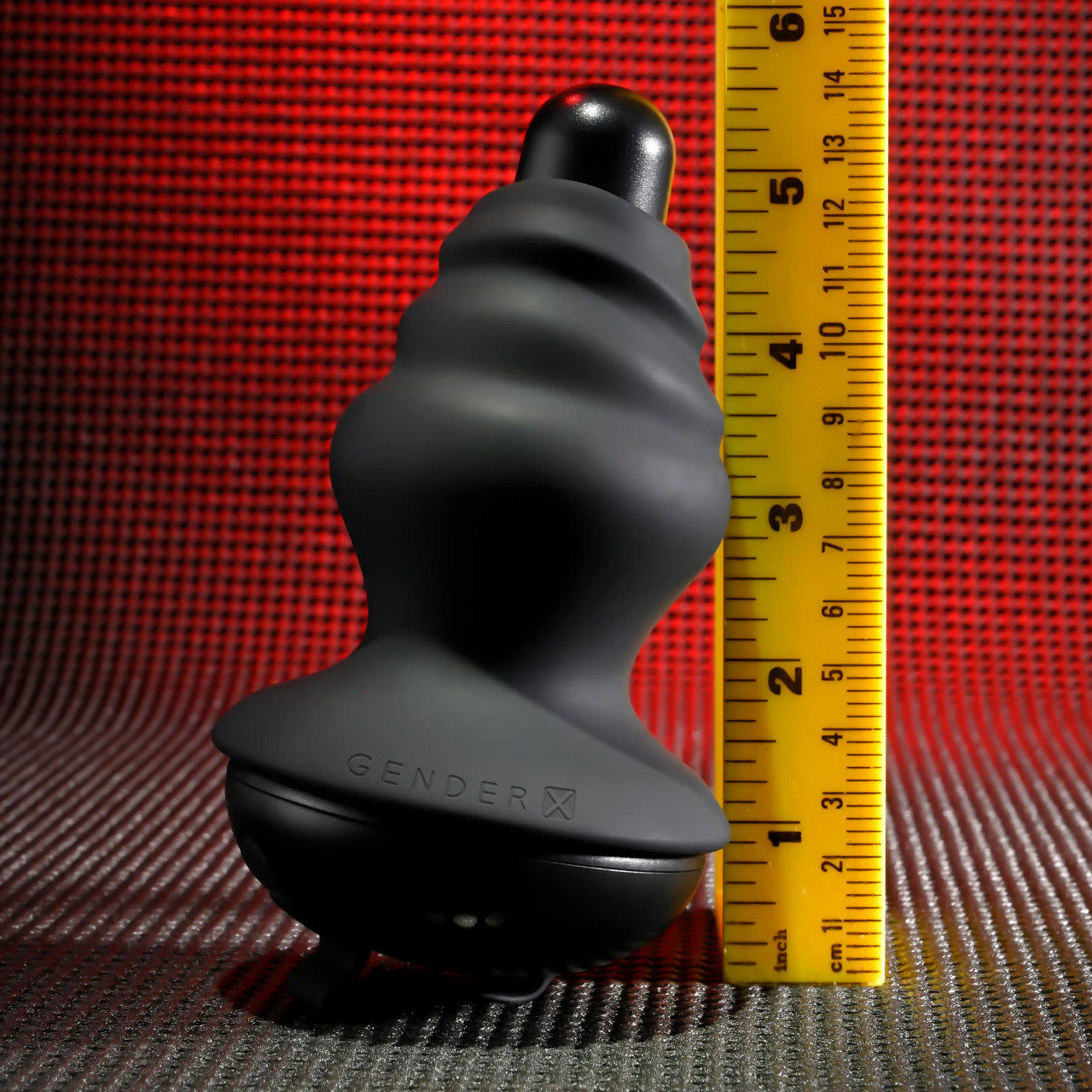 Black silicone vibrating shaft with a textured surface and a flared base, next to a yellow ruler.