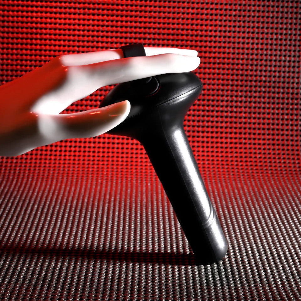 A white mannequin hand holds a black vibrating shaft with a red textured background.