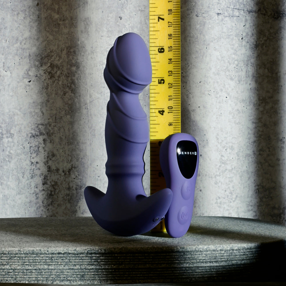 Purple remote-controlled sliding ring vibrator with textured head and remote, shown next to a yellow ruler on a gray surface.
