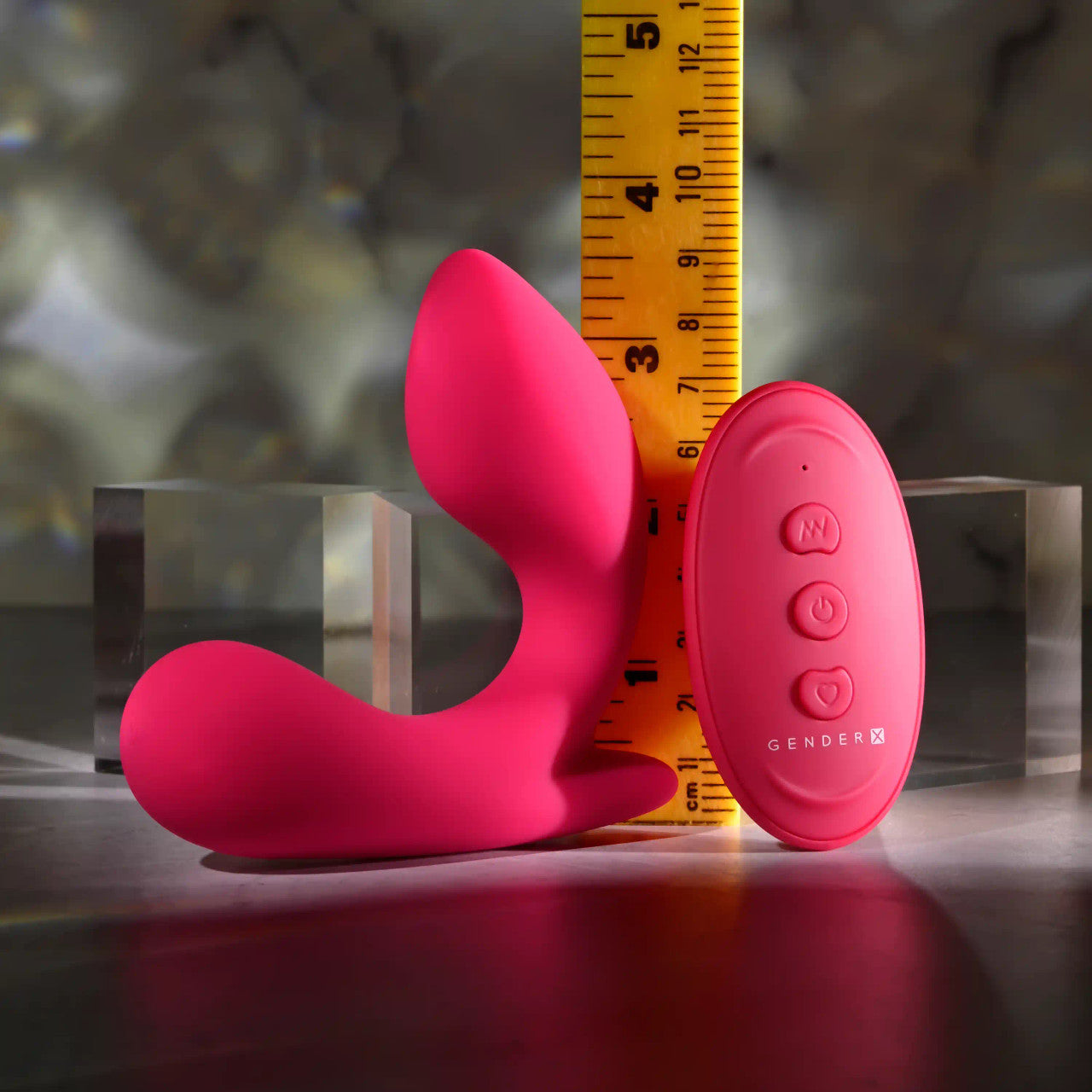 Pink remote-controlled vibrating prostate massager with a ruler for scale.