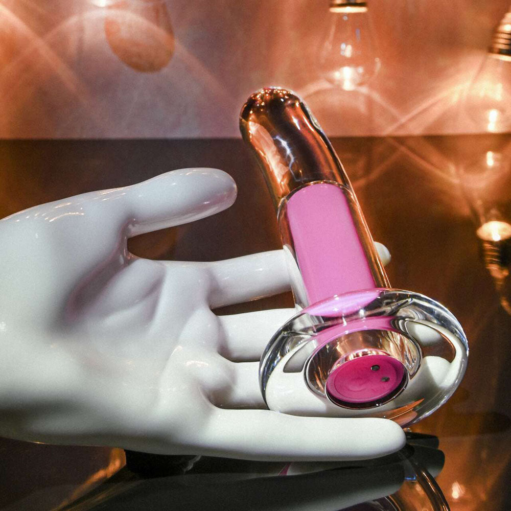 White gloved hand holding a pink and gold vibrating anal plug with a clear base.