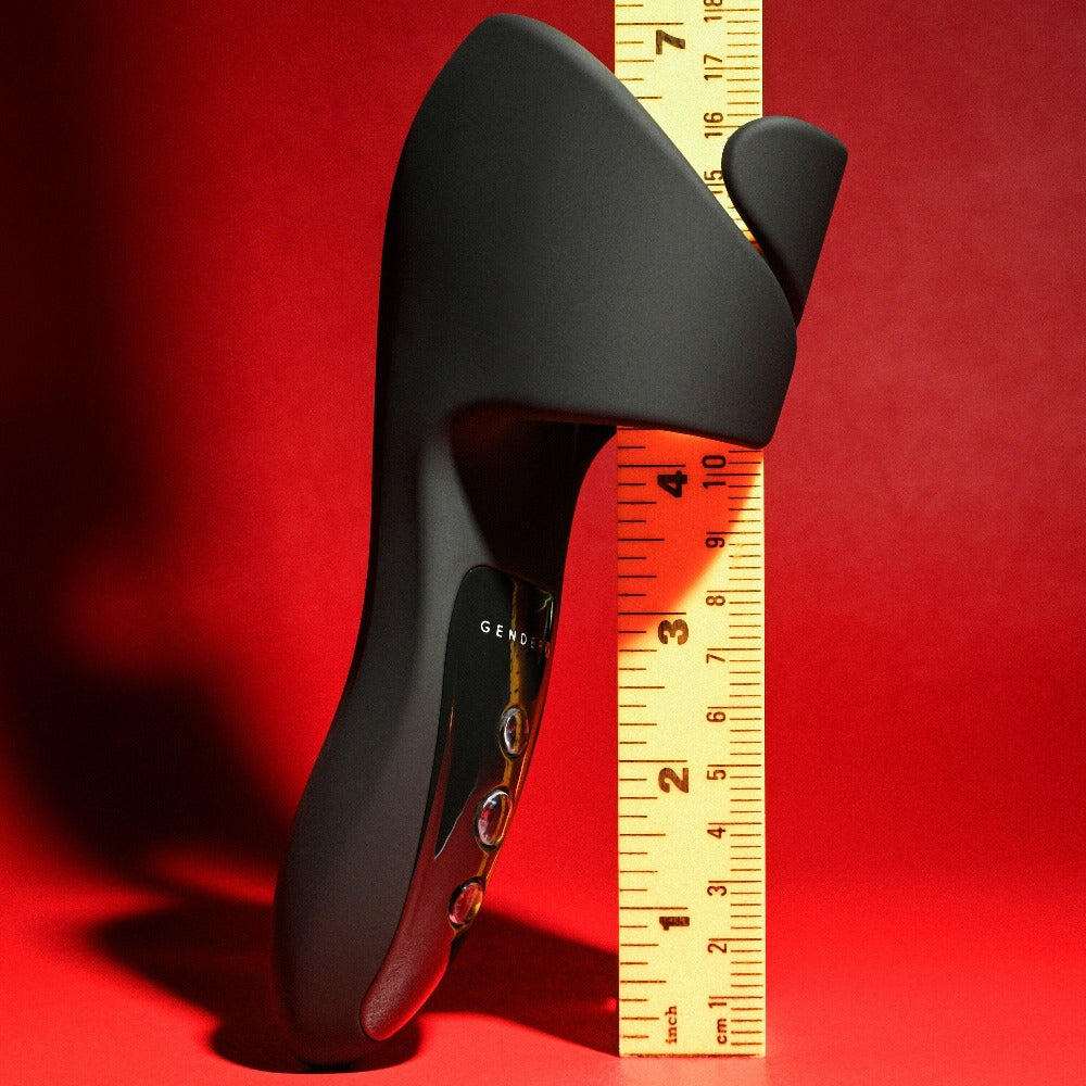 Black cradle vibrator with a ruler measuring its length against a red background.