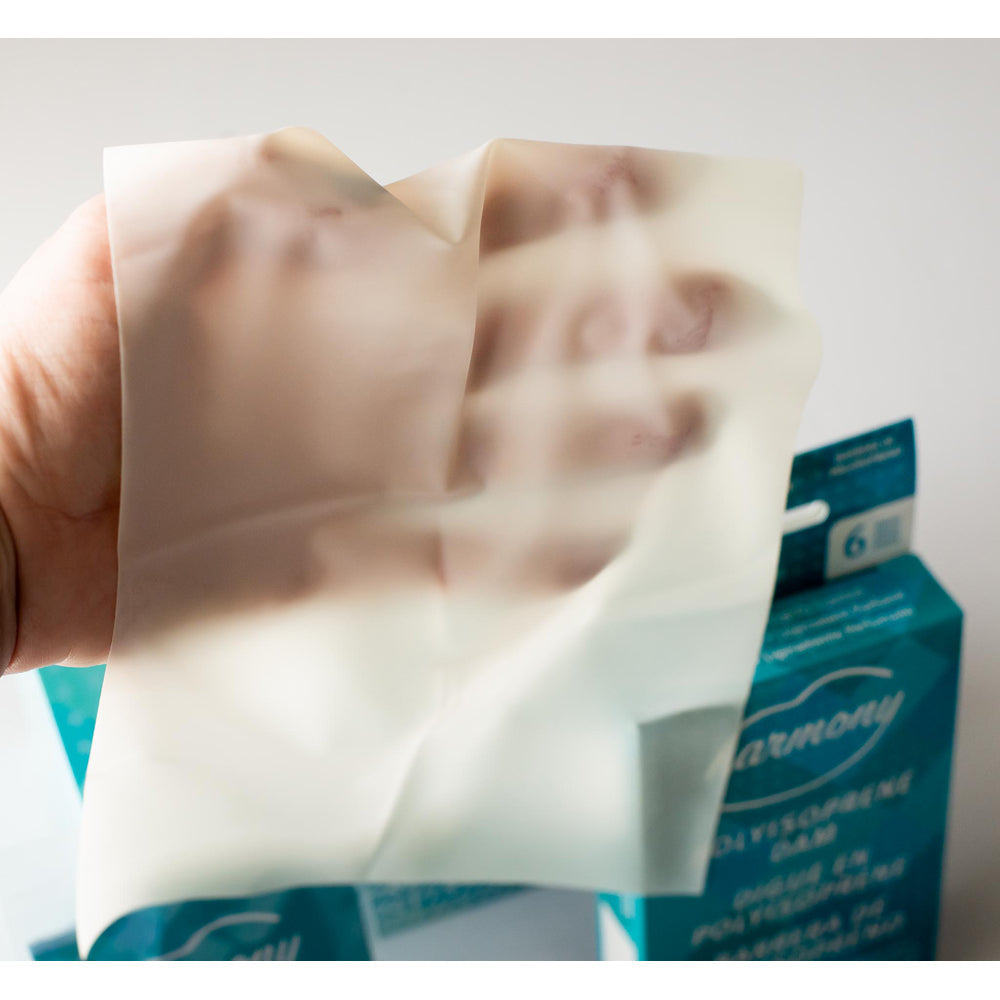 Harmony Latex Oral Dams in natural color held by a hand.