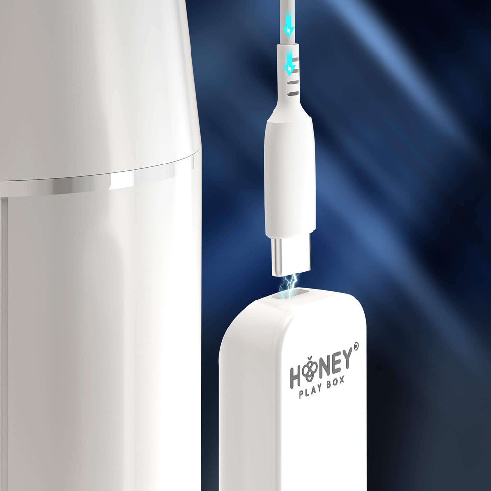 White charging cable connecting to a white Honey Play Box device.