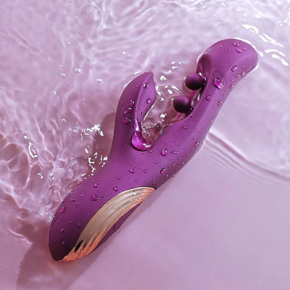 App-controlled purple rabbit vibrator with twin balls and gold accents in water.