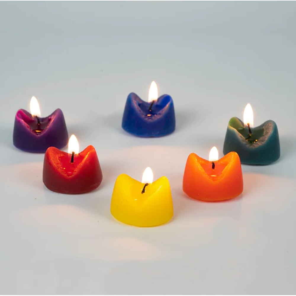 Six vibrantly colored, anus-shaped scented candles with lit wicks.