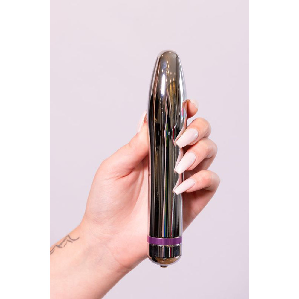 A silver metal rocket vibrator with a purple band is held in a hand.