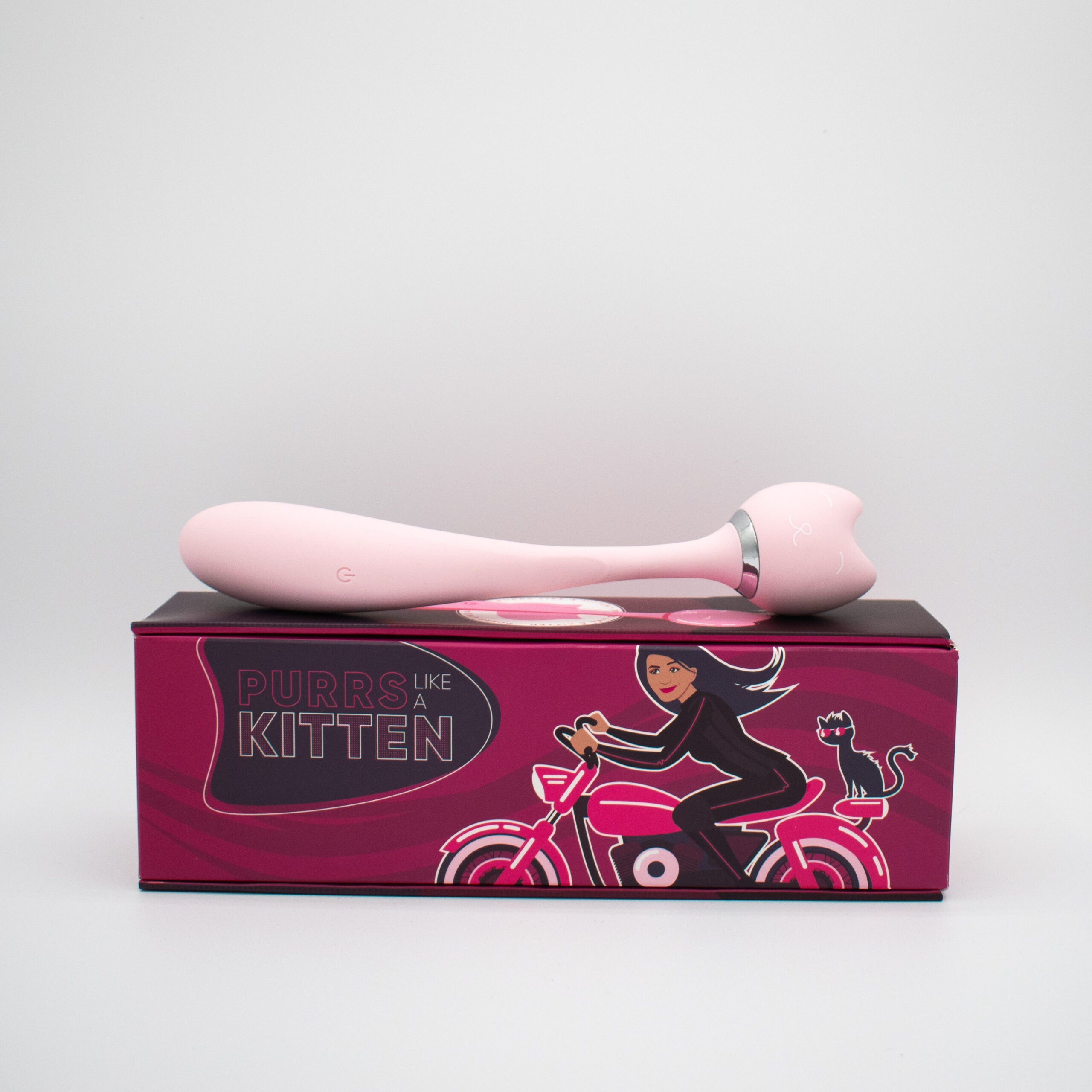A pink wand vibrator rests on a box with a cat-themed design.