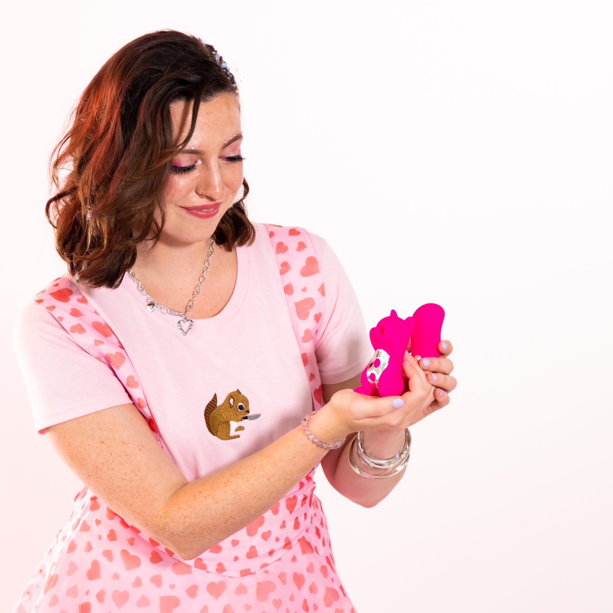 A woman holds a pink squirrel-shaped vibrator with air pulse and G-spot stimulation.