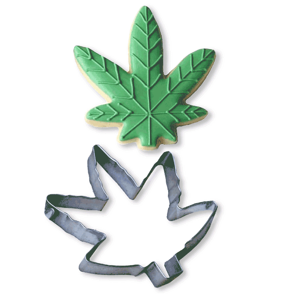 A green cannabis leaf cookie and a metal cookie cutter.