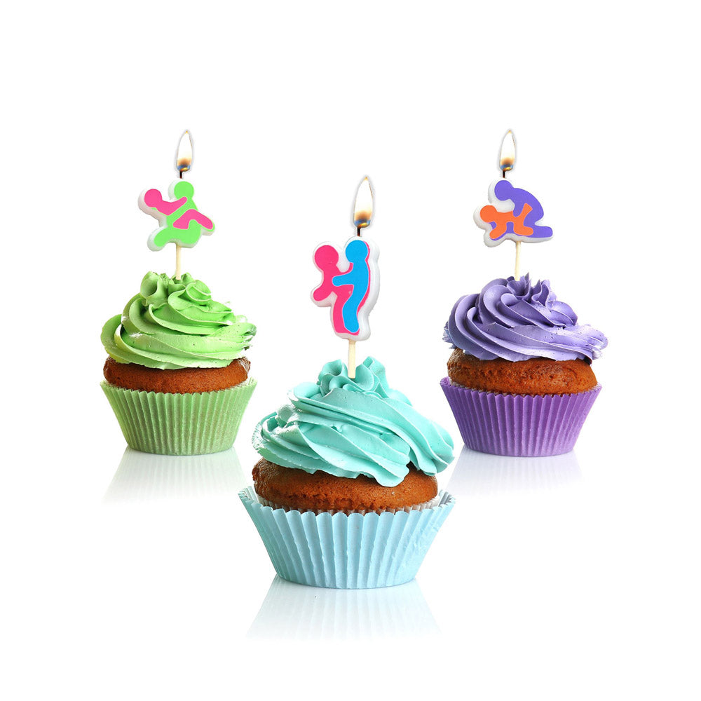 Three novelty candles in sexual positions atop cupcakes.