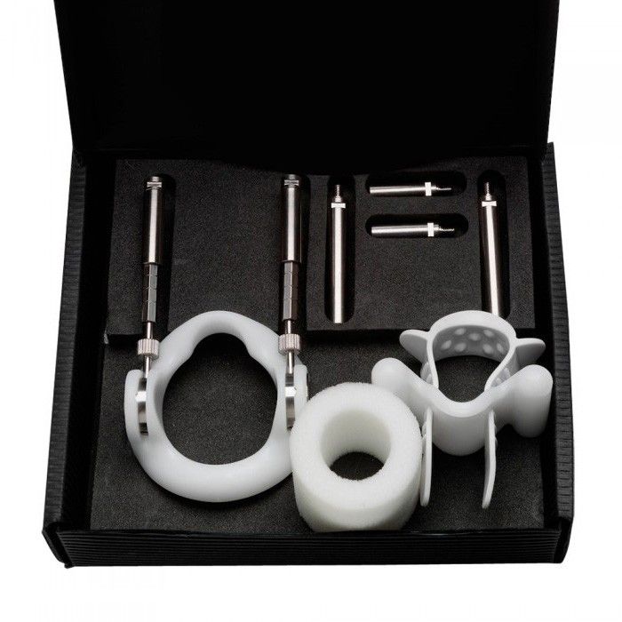 Penis extender kit with white plastic and metal components in a black box.