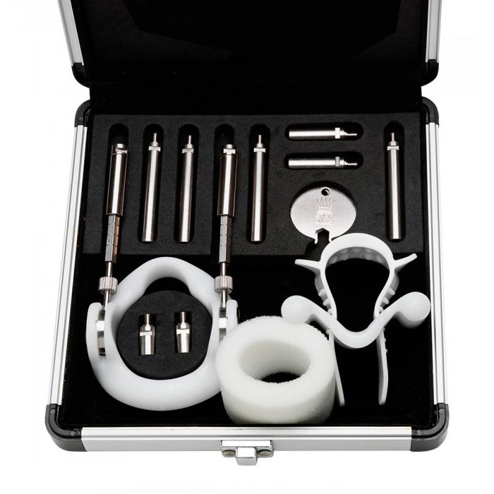 A penile extender kit with titanium rods and a white plastic device in an aluminum case.