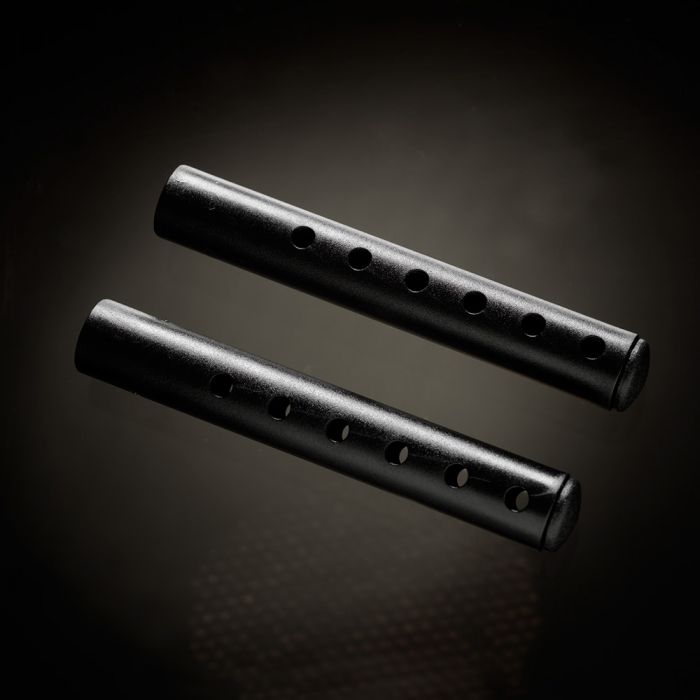 Two black penis extenders with multiple holes on a dark background.