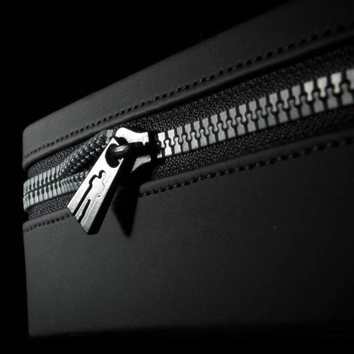 Black travel bag with a silver zipper and pull tab.