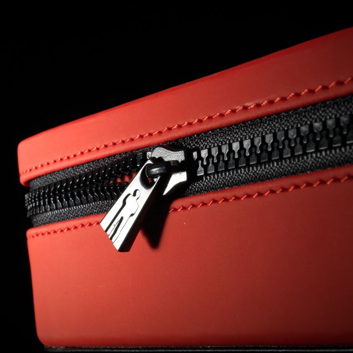 Red and black penis enlargement device with zipper and pull tab.