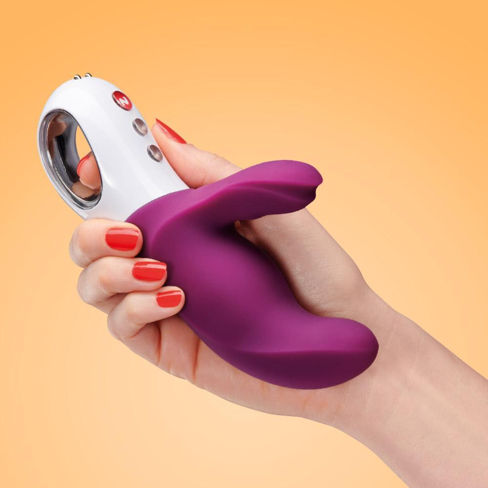 A purple and white dual motor rabbit vibrator held in a hand.
