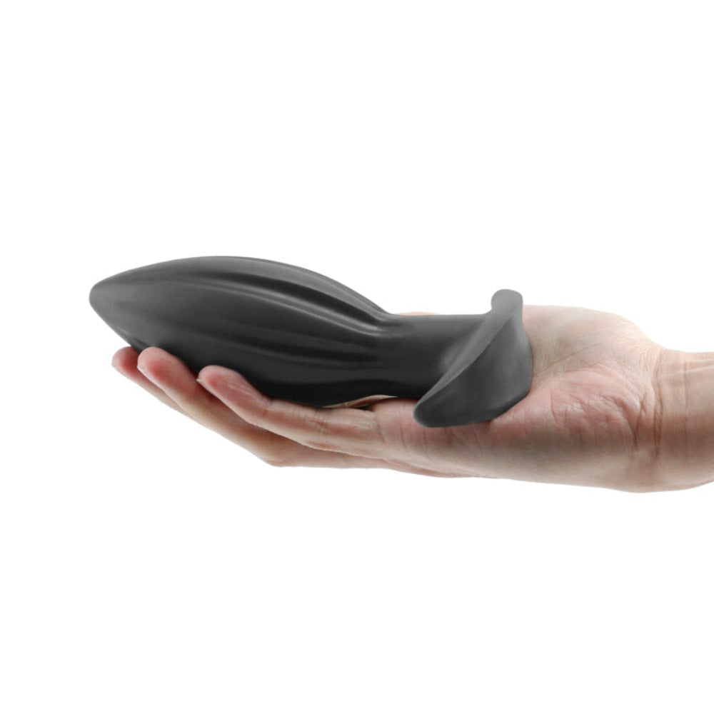 Medium black silicone expandable anal plug held in a hand.