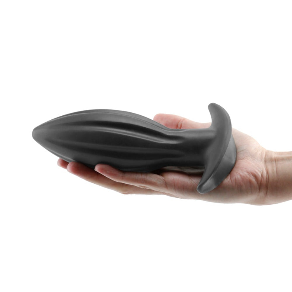 A black, ribbed silicone plug with a flared base rests in a hand.