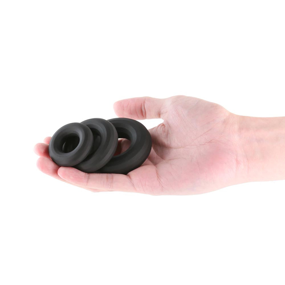 Three black silicone rings of varying sizes held in a hand.