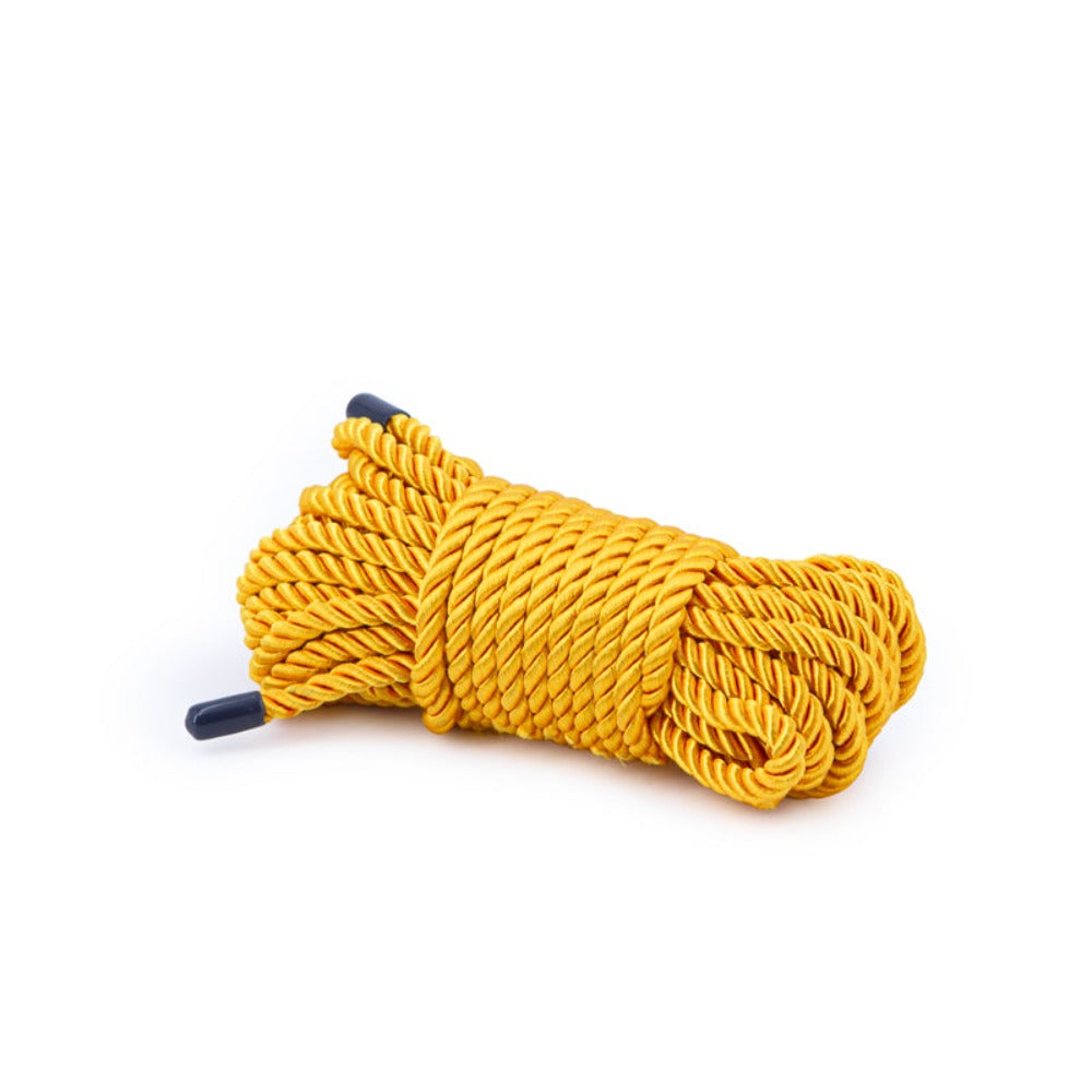 A coiled gold rope with dark blue tips on a white background.