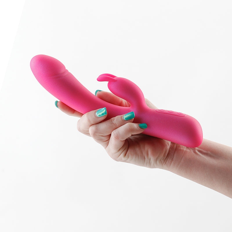 A pink silicone vibrator with rabbit ears held in a hand.