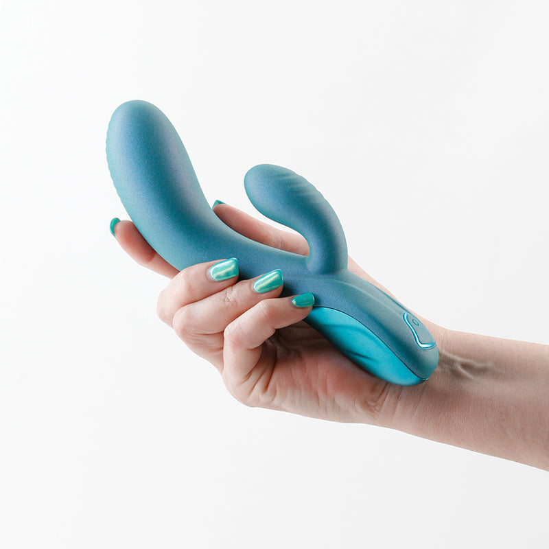 A metallic green silicone vibrator held in a hand with matching nail polish.
