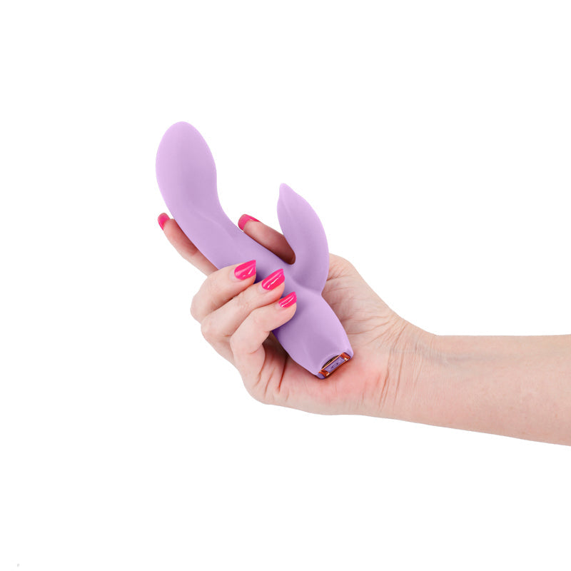 A light purple silicone vibrator with two ear-like protrusions held in a hand.
