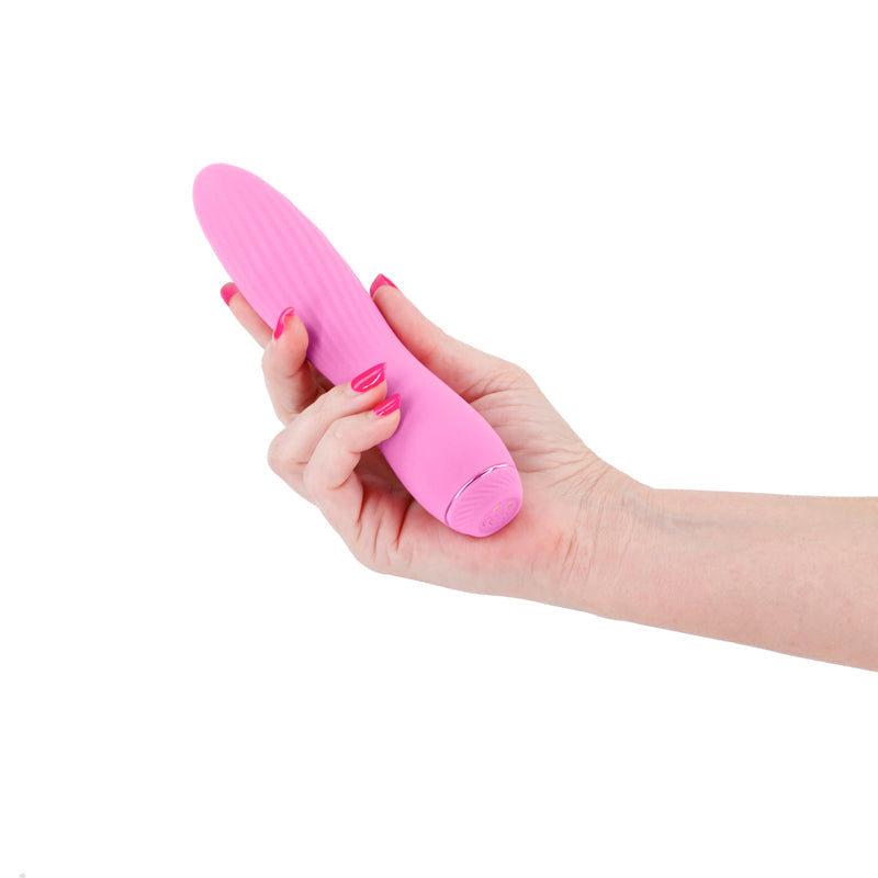A light pink ribbed silicone vibrator held in a hand.