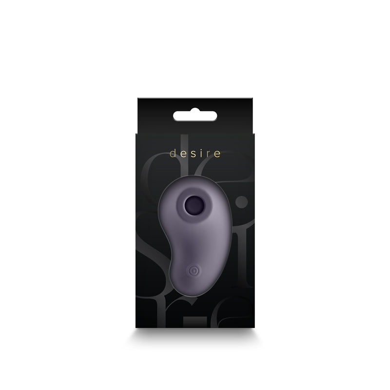 A grey, pebble-shaped stimulator with a dark circular opening and a small button on a black box with the word "desire" in gold.