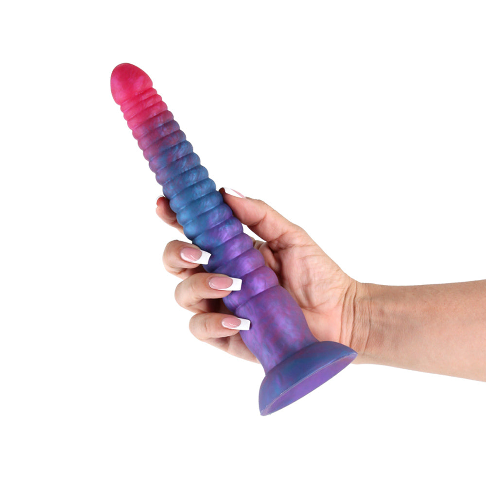 A hand holds a 9-inch pink and blue stacked silicone dildo.