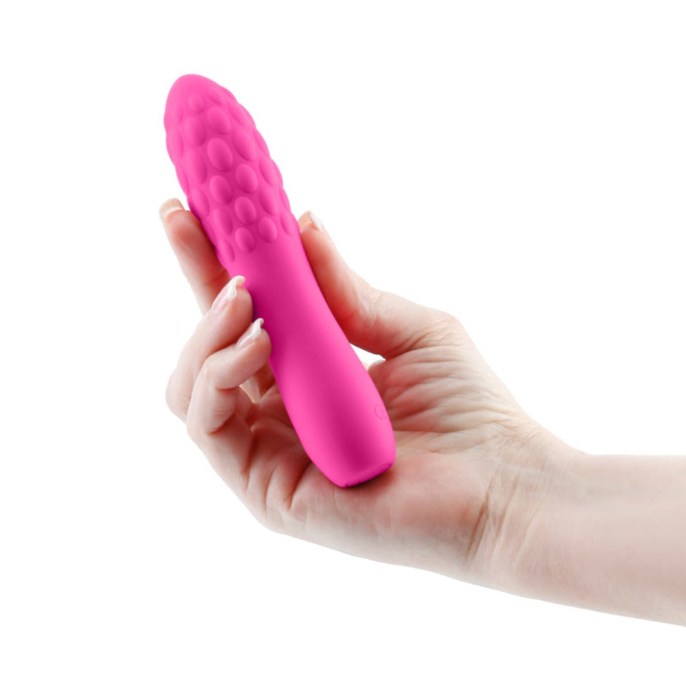 Pink textured silicone massager held in a hand.