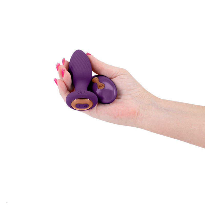 Purple vibrating remote control anal plug held in a hand.