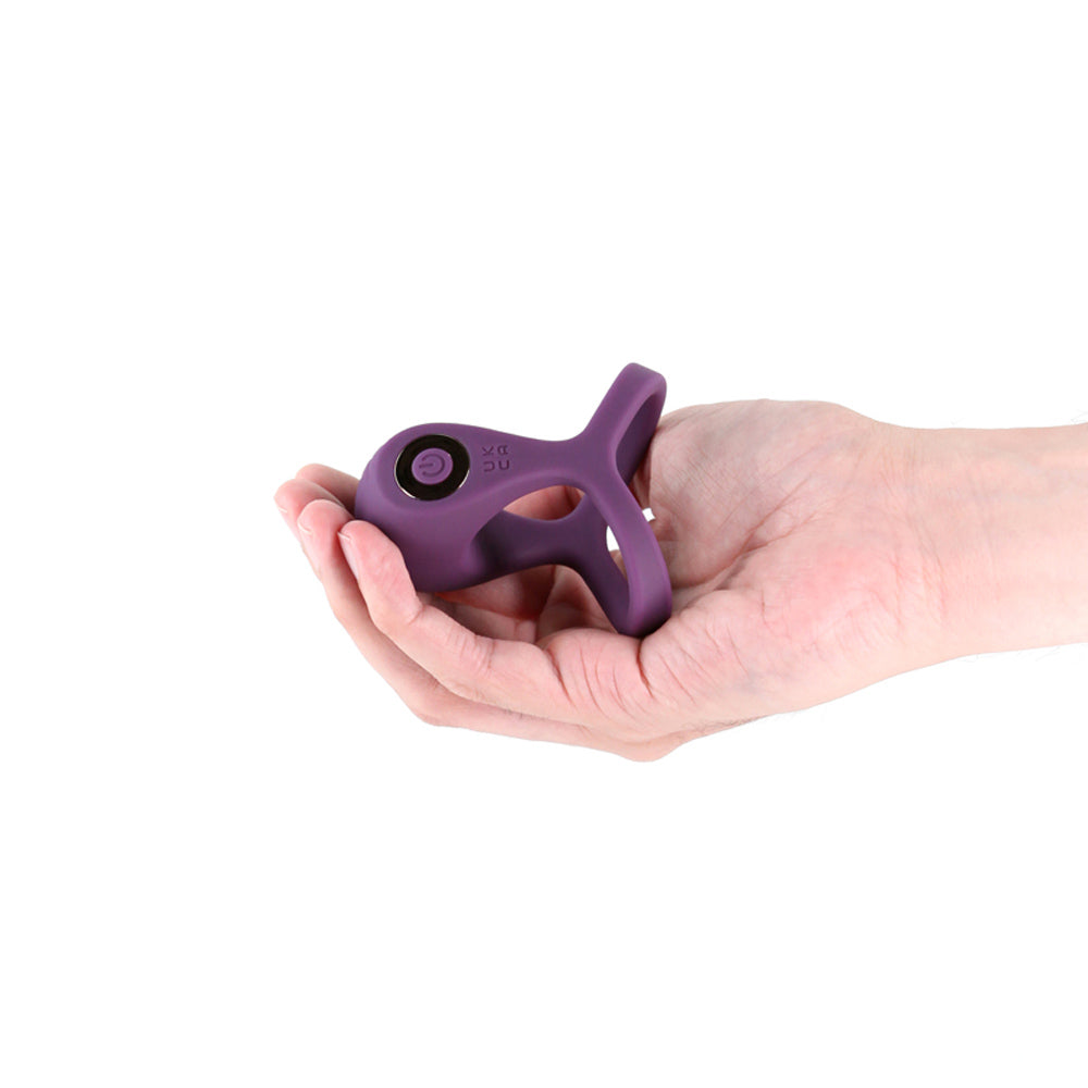 A purple vibrating silicone cock ring held in a hand.