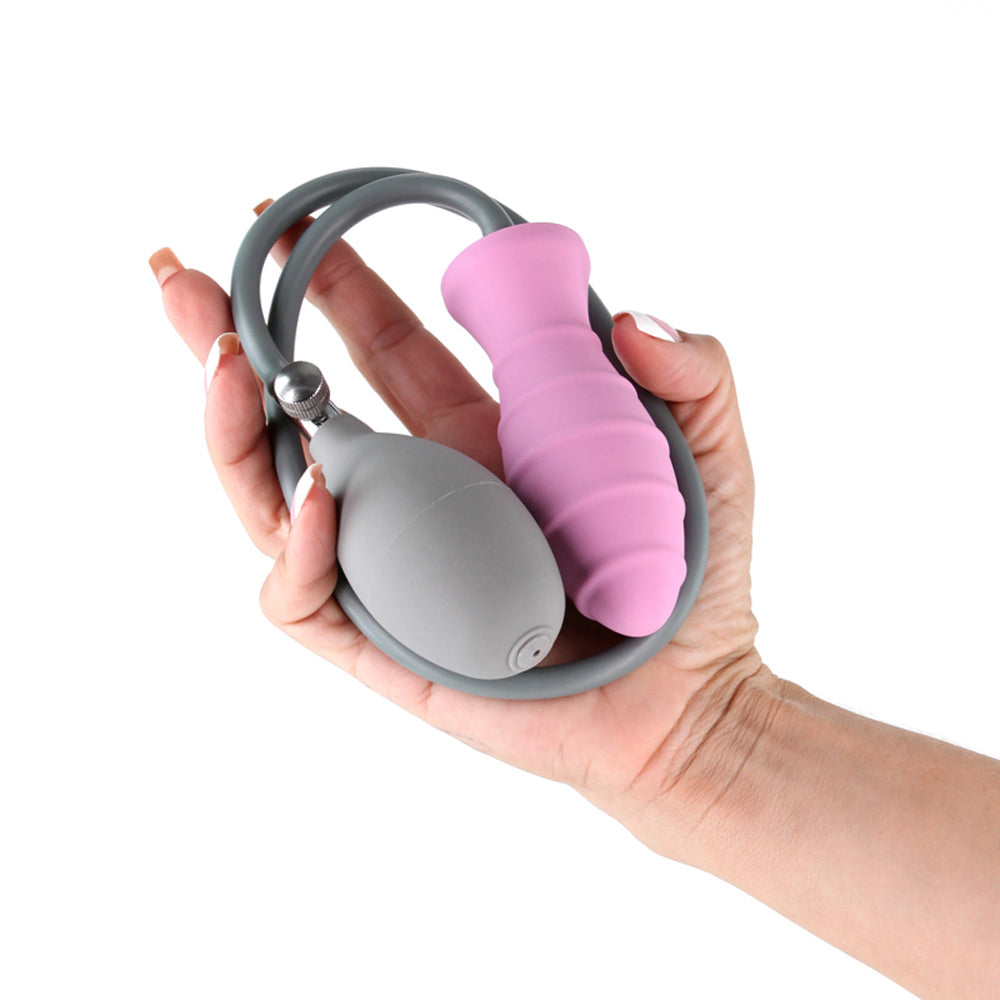 Pink inflatable anal plug with rigid core and grey bulb held in a hand.