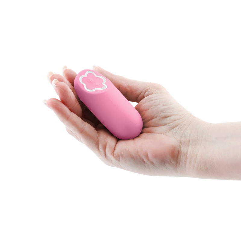 A pink, oval-shaped vibrator with a flower-shaped button held in a person's hand.