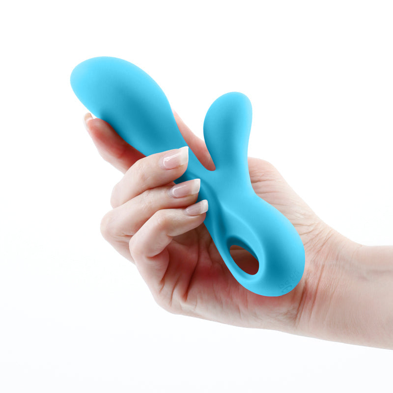 A blue dual motor silicone vibrator held in a hand.