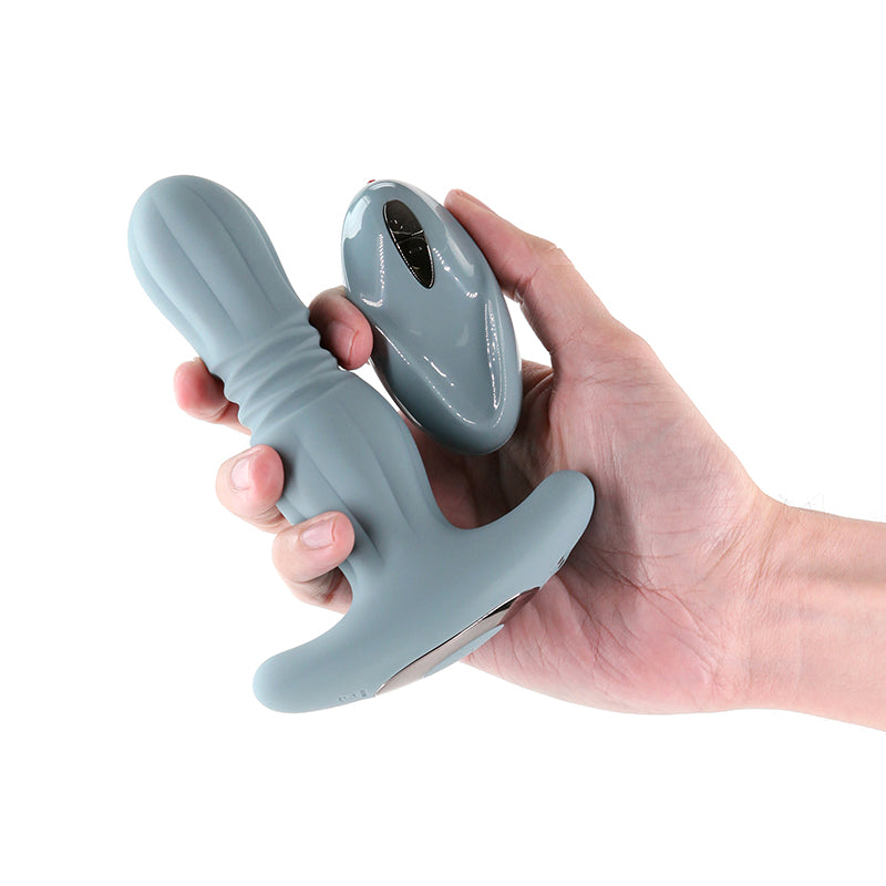 Gray silicone prostate massager with a remote held in a hand.