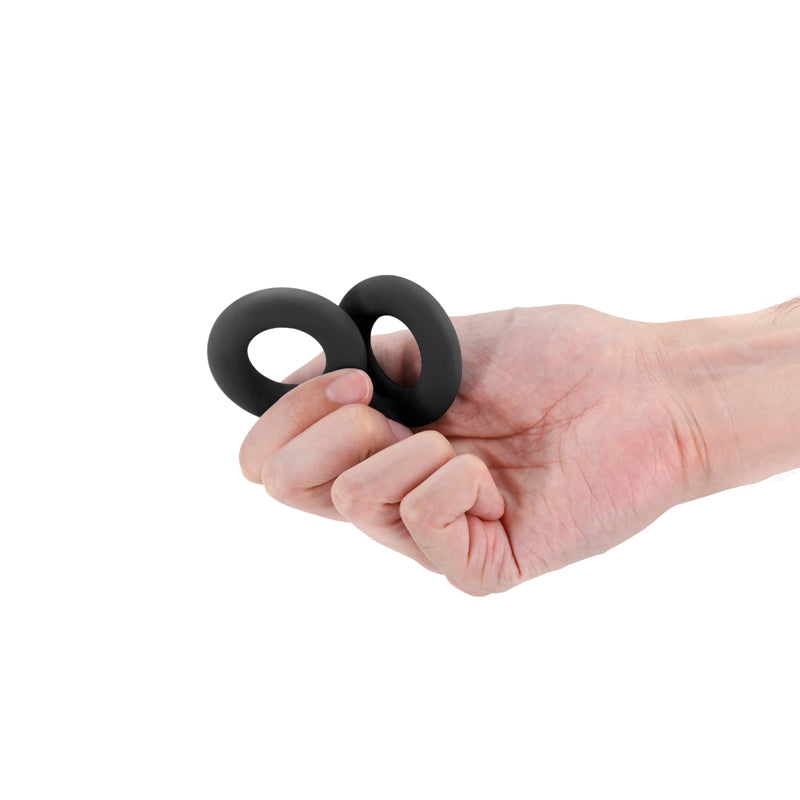 Two black stretchy cock rings held in a hand.