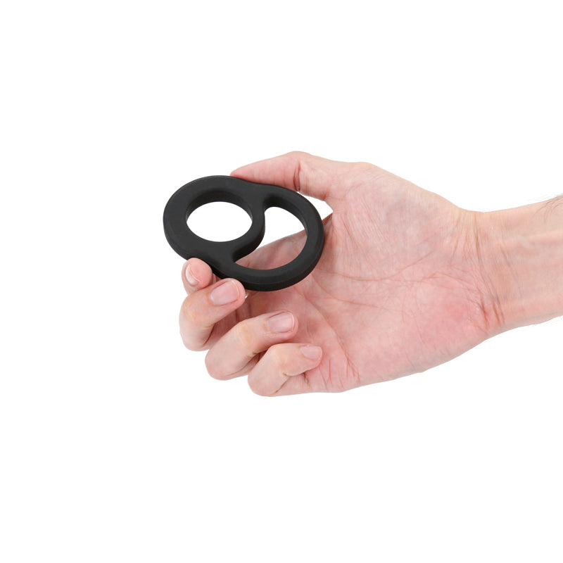 Black stretchy cock ring held in a hand.