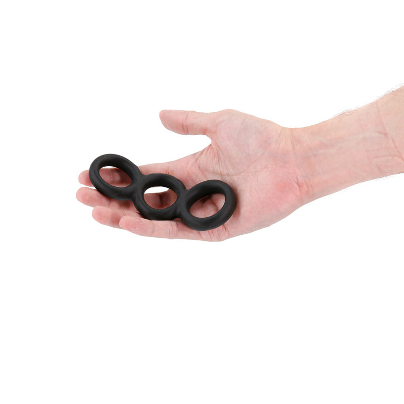Black threefold stretchy cock ring held in a hand.