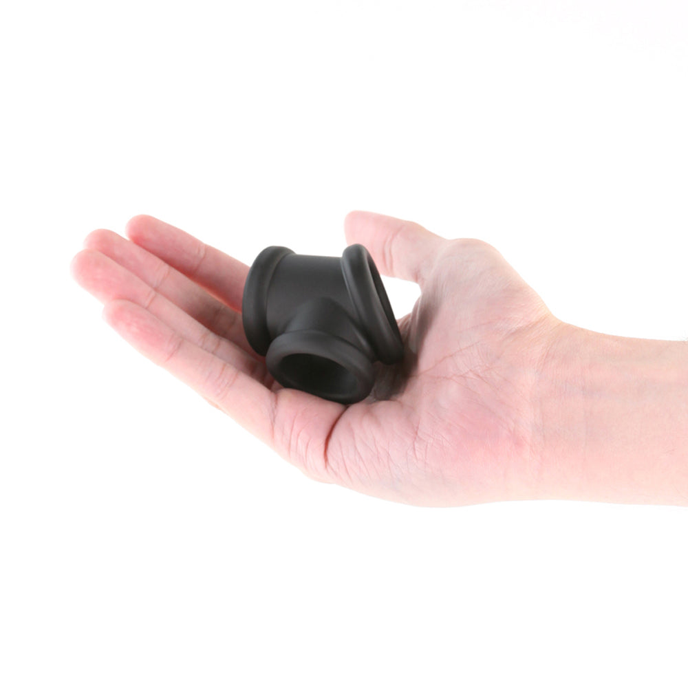 Black silicone cock and ball ring held in a hand.