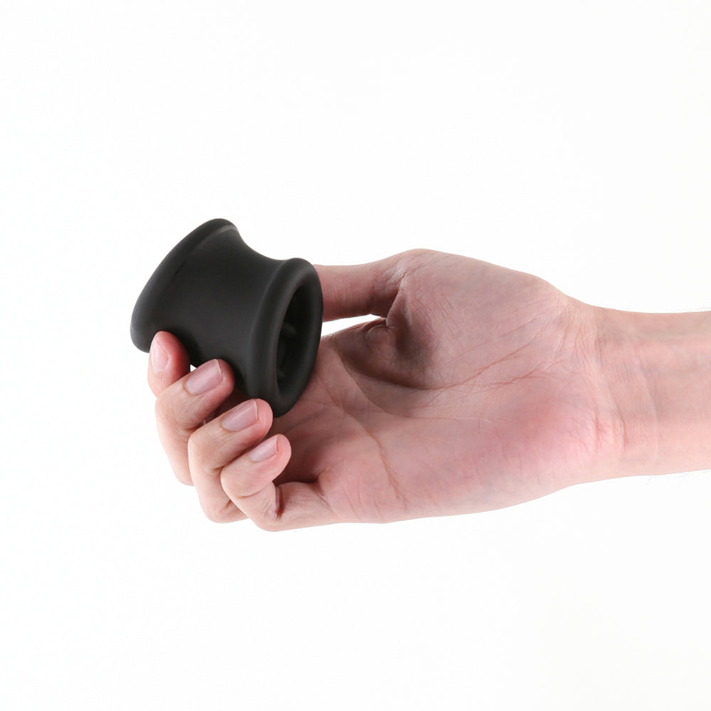 Black silicone ball stretcher held in a hand.