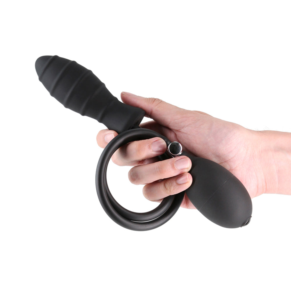 A black inflatable anal plug with a rigid core and pump held in a hand.