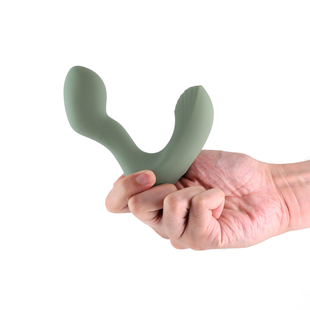 A green silicone prostate massager held in a hand.