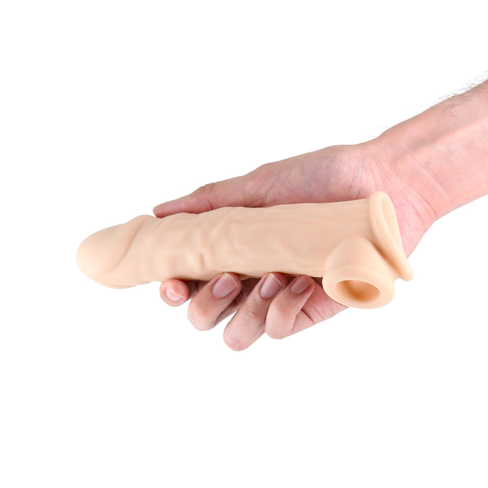 Flesh-toned textured silicone enhancer sleeve held in a hand.