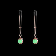 Adjustable rose gold nipple clamps with silicone tips and glowing green charms.