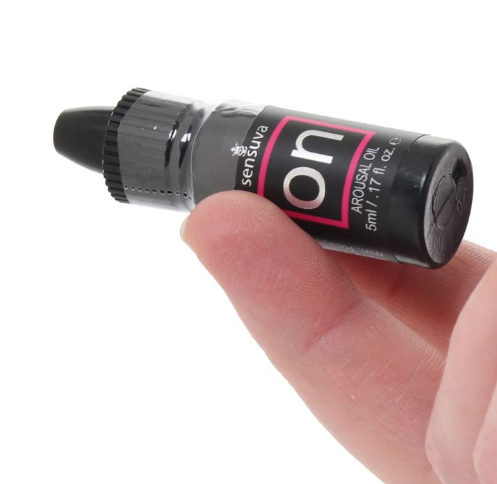A small black bottle of Sensuva arousal oil with a pink and white label.