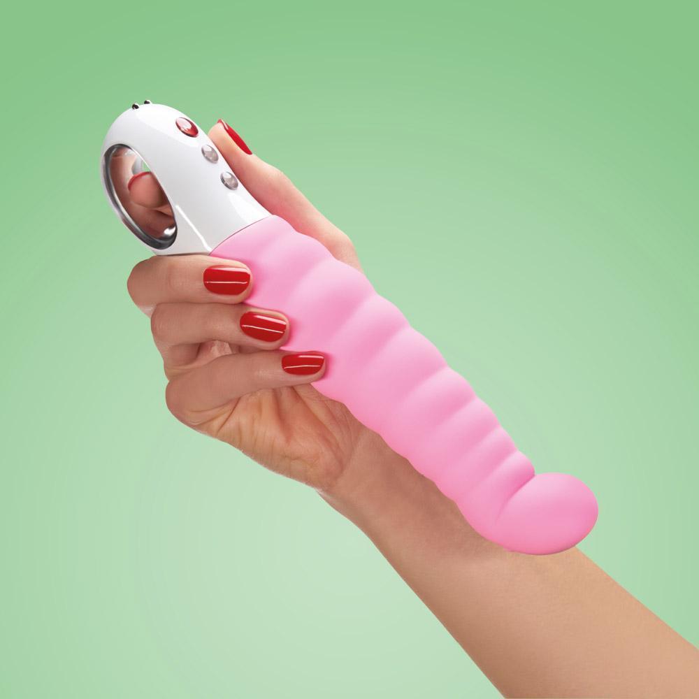 A pink, ribbed vibrator with a white handle is held by a hand with red nail polish.